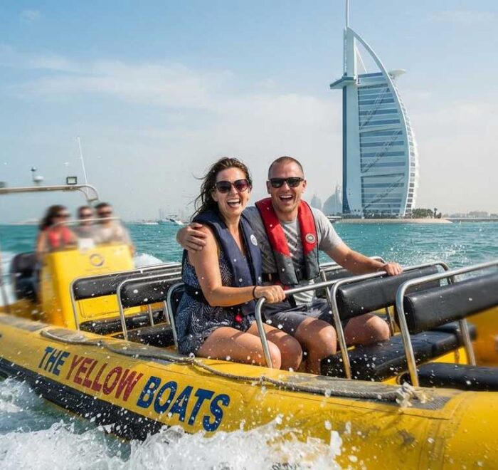 Yellow boat tour dubai couple smiling on boat splashing sea waves